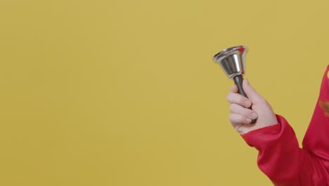 close up girl in festive outfit ringing bell with copy space