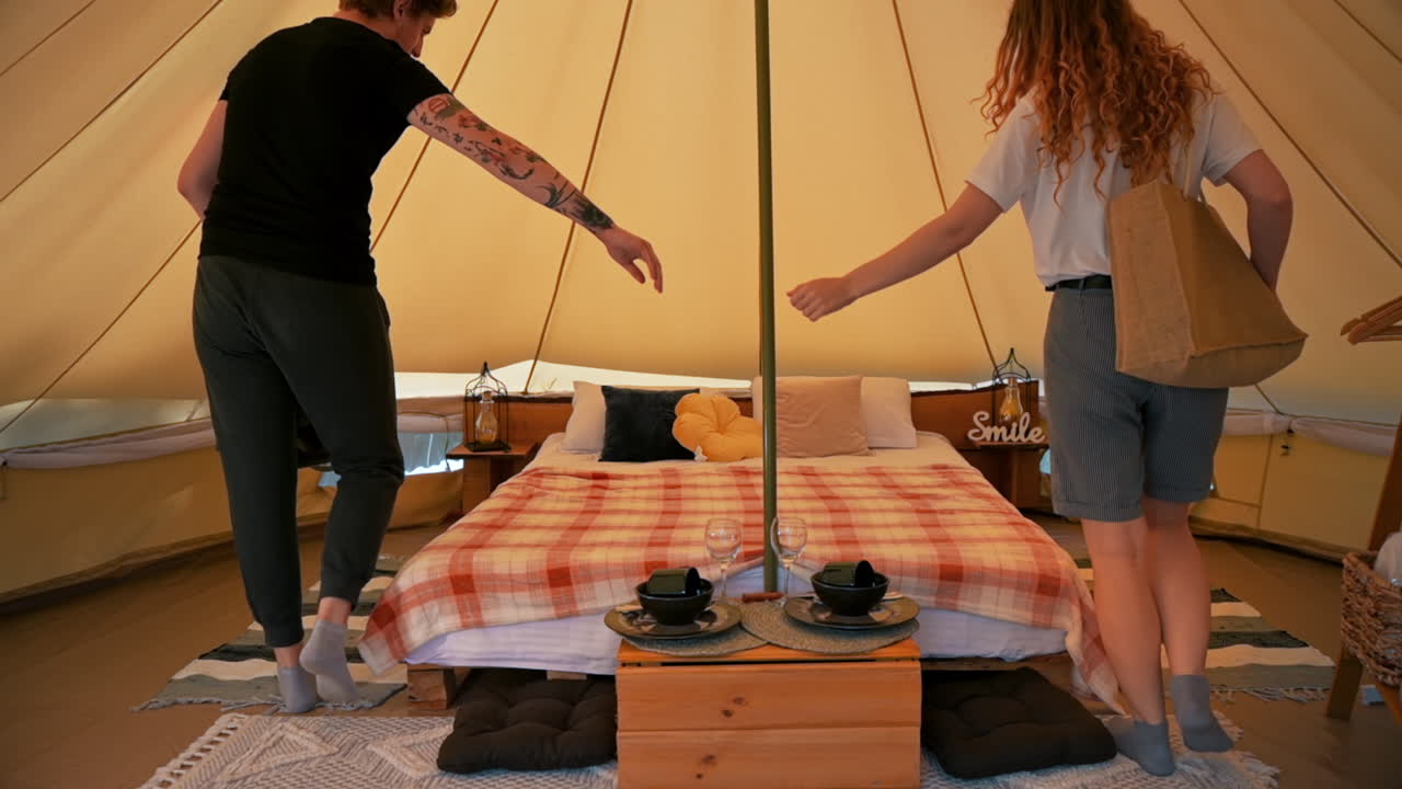 Couple entering the tent and sitting on the bed. Young man and woman. Glamping. Slow motion