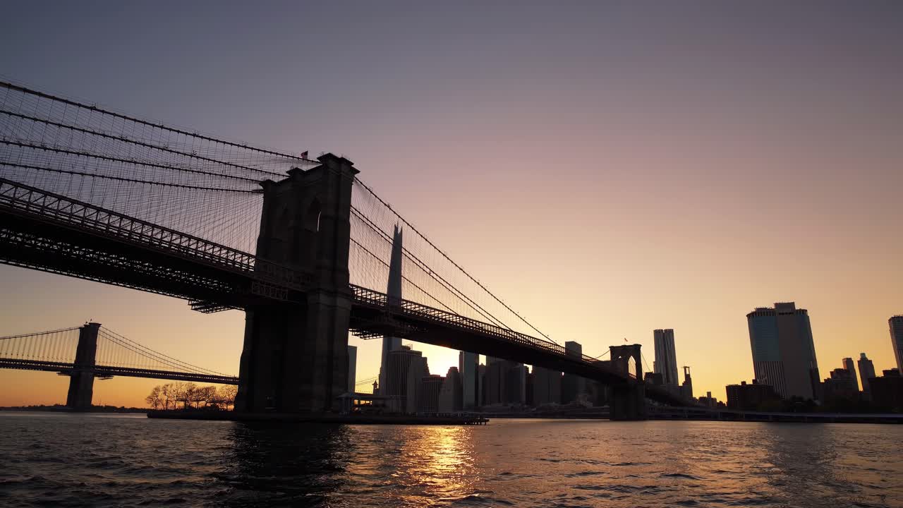 A stunning low-angle video shot of a bridge at sunset, capturing the silhouette of the city skyline