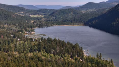 vista panorámica del lago paul en la columbia británica rodeada de montañas cubiertas de árboles cerca de kamloops