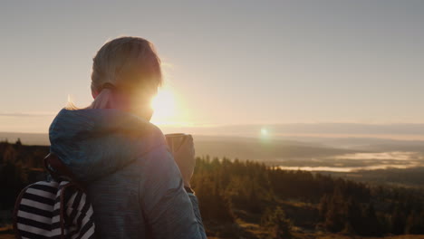 el viajero bebe té caliente en la cima de la montaña admirando el amanecer en el horizonte naturaleza de