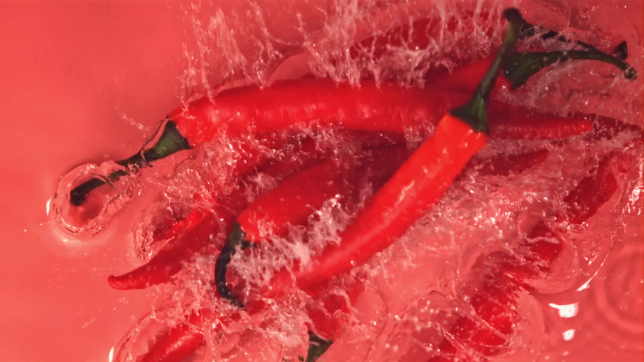Peperoncini rossi freschi che schizzano in acqua al rallentatore