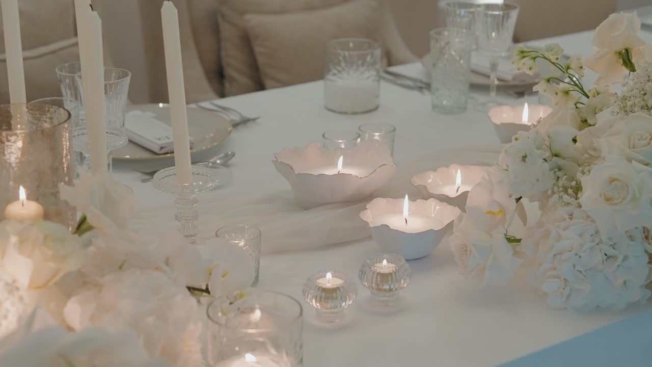 Soft candlelit white tablescape with delicate flowers and glassware