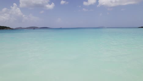 Tranquil-aerial-wide-shot-of-water-crashing-on-the-beach-shore-sand-blue-sky-white-clouds-turquoise-water-relaxation-vacation-tourism