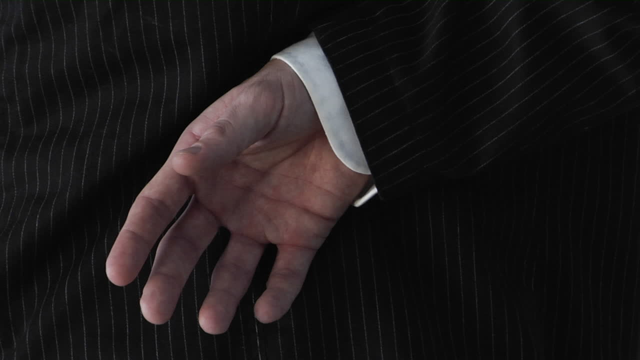 En forretningsmand krydser fingrene bag ryggen.