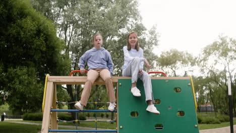 Little-girl-with-down-syndrome-talking-with-her-blonde-friend-in-the-park.-Then-other-boy-approachs-and-greets-them