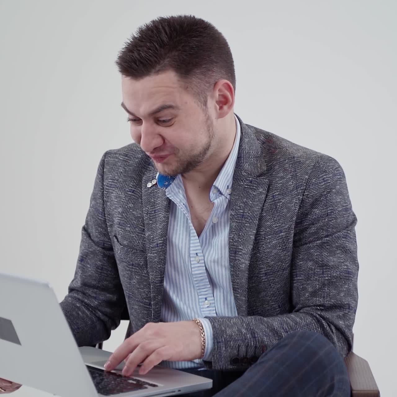 Bearded man looking into laptop. Handsome businessman in costume becomes very sad when finds bad information in his gadget. Slow motion.