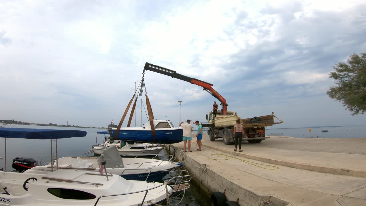 Lifting boat from the sea with crane on a truck