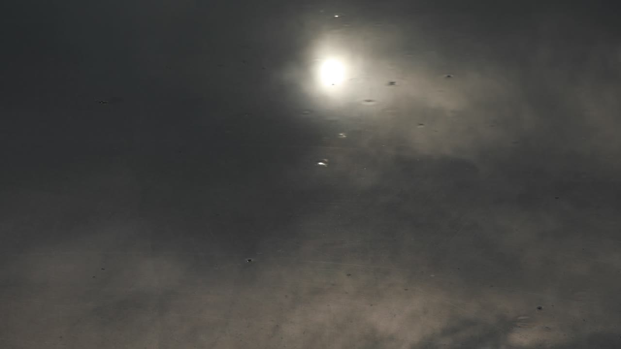 태양과 구름을 반사하는 반짝이는 금속성 지붕의 부드러운 빗방울