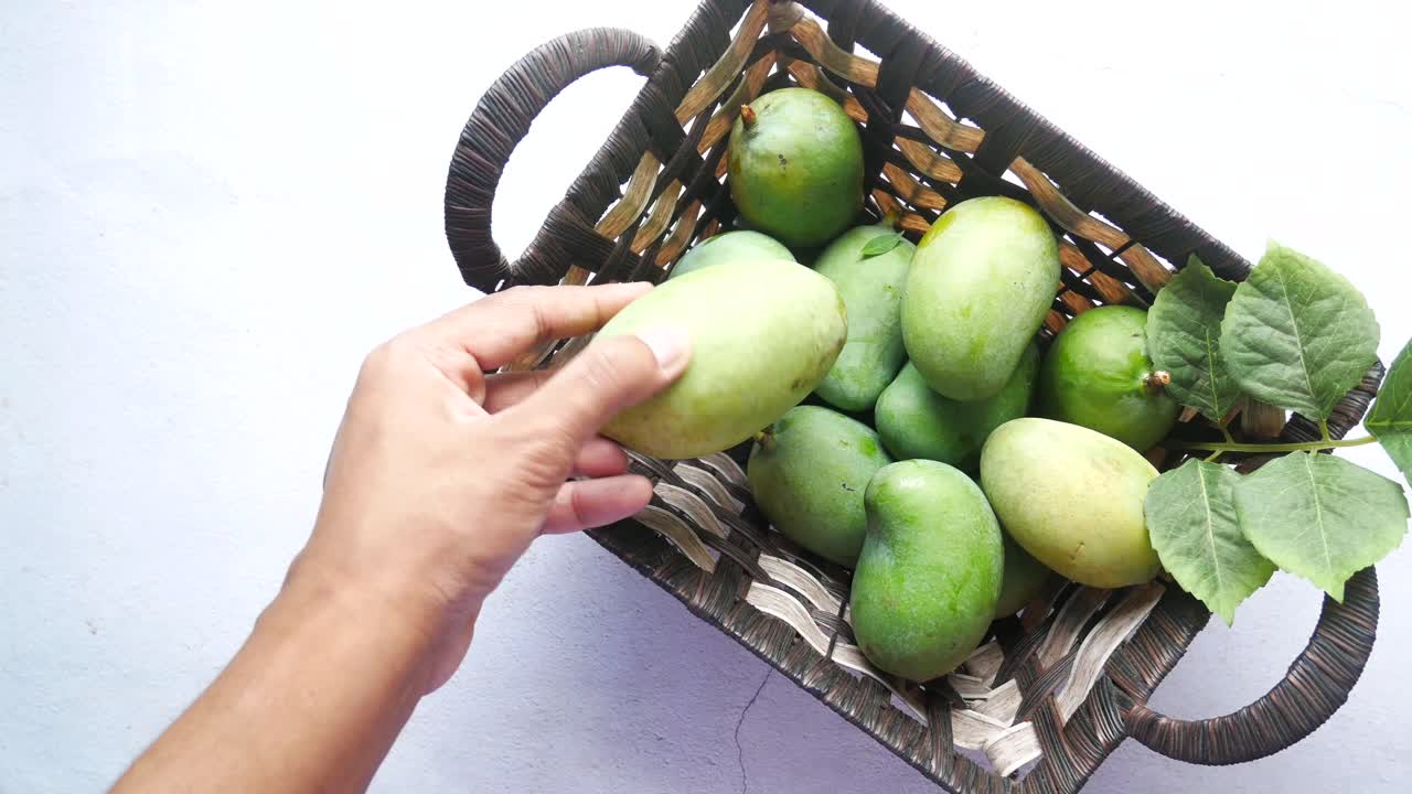 recogiendo mangos a mano de una canasta