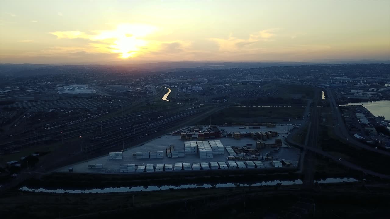 imágenes de la puesta de sol con vistas a los yates amarrados con tráfico en una carretera y contenedores de envío para ser transportados a los barcos por camiones