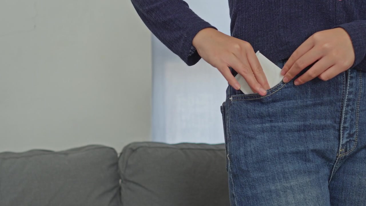 Close-up of woman putting packaged sanitary liner into pocket for feminine hygiene care