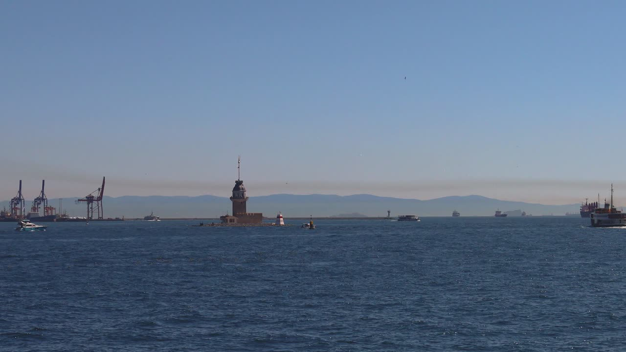 Long shot of multiple boats sailing across the Bosphorus at sunset glow with city silhouette in background