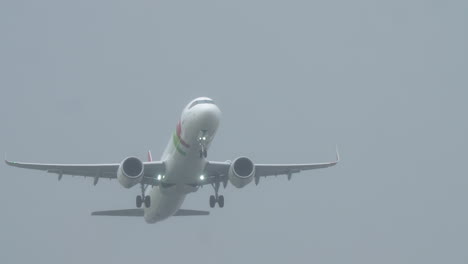 lisbon, portugal - april 1, 2025: a tap portugal aircraft takes off at humberto delgado airport in foggy weather conditions. the plane lights are on and a red-and-white windsock is visible on the right side of the runway