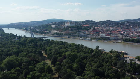 wide aerial revealing shot of green park and bratislava, capital of slovakia - summer sunny day