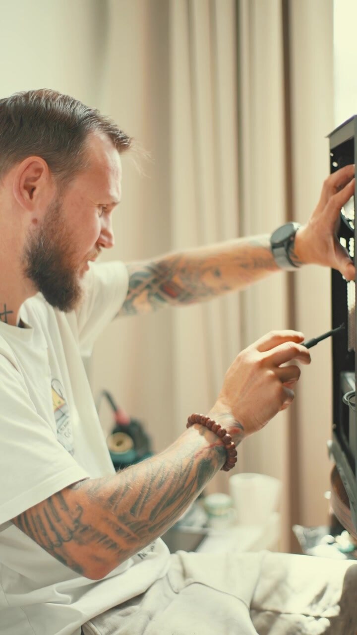 Man repairs equipment in a welllit room with light curtains and modern decor