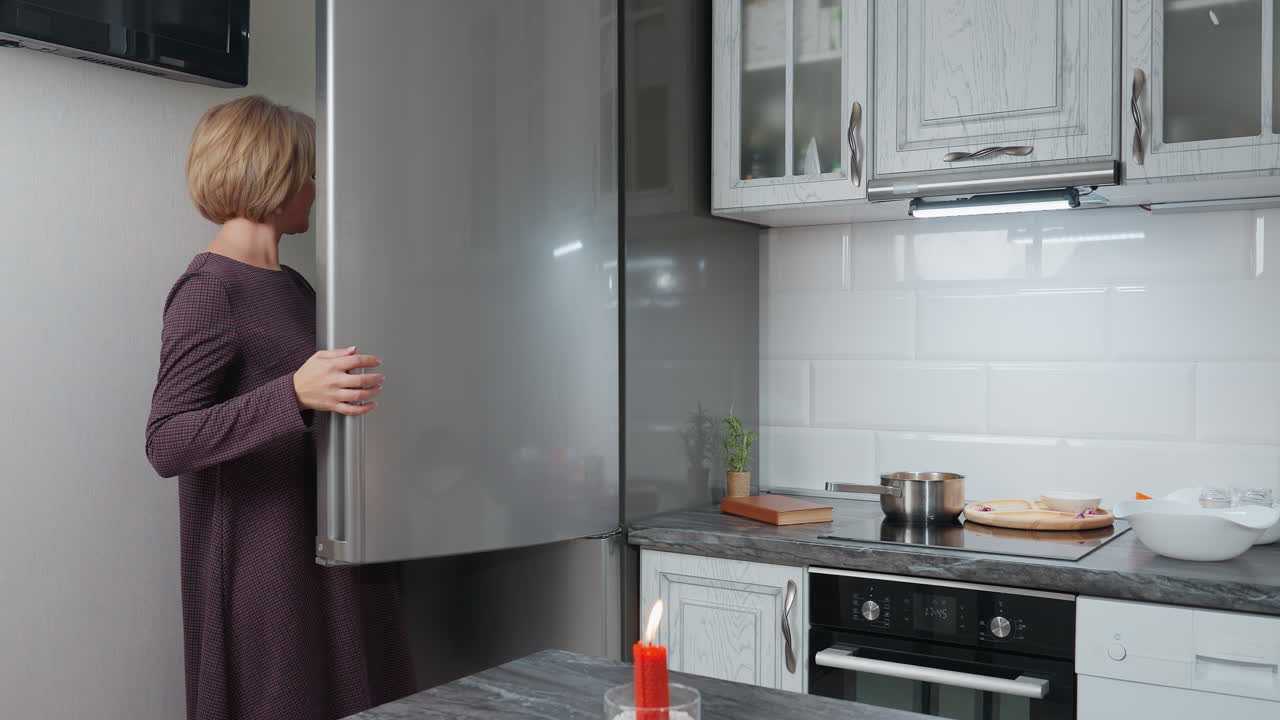 mujer abre el refrigerador para recuperar la caja de huevos y la coloca en la encimera en la cocina moderna, la escena captura la rutina diaria, la preparación de alimentos y el espacio de cocina bien organizado con iluminación cálida