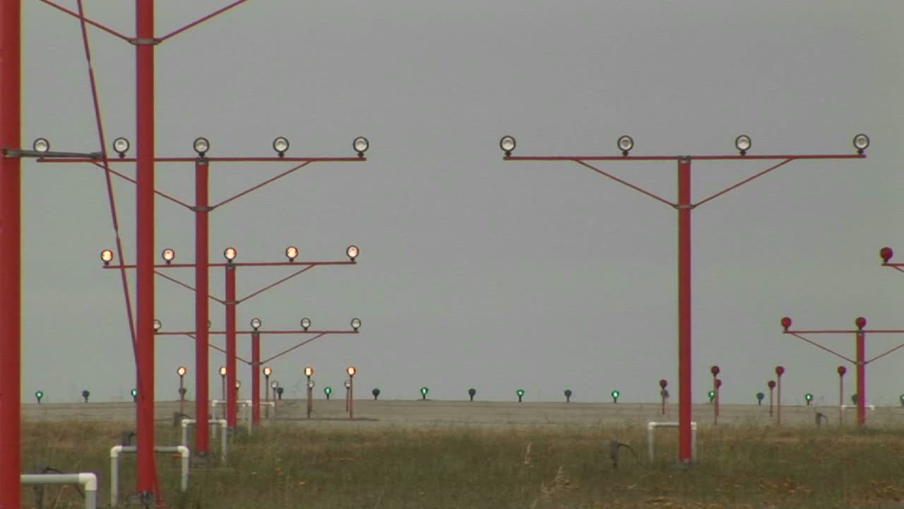 un avión que aterriza en una pista a través de luces y haces de equipos de guía