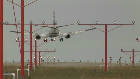 un avión que aterriza en una pista a través de luces y haces de equipos de guía
