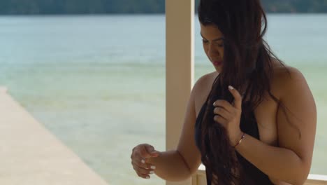 nena en bikini se para y juega con su cabello en una cabaña en la playa