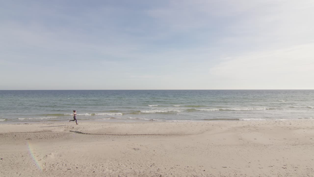 바다 지평선 옆 열대 해변에서 조깅하는 건강한 젊은 여성