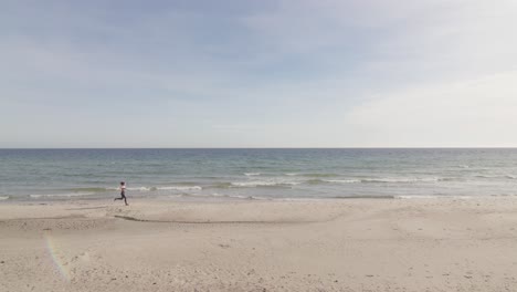 Young-healthy-woman-jogging-on-tropical-beach-by-the-ocean-horizon