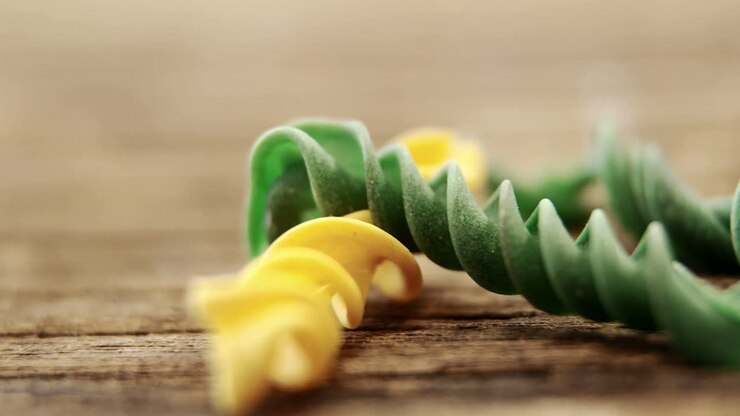 Pasta gemelli gialla e verde su tavolo di legno
