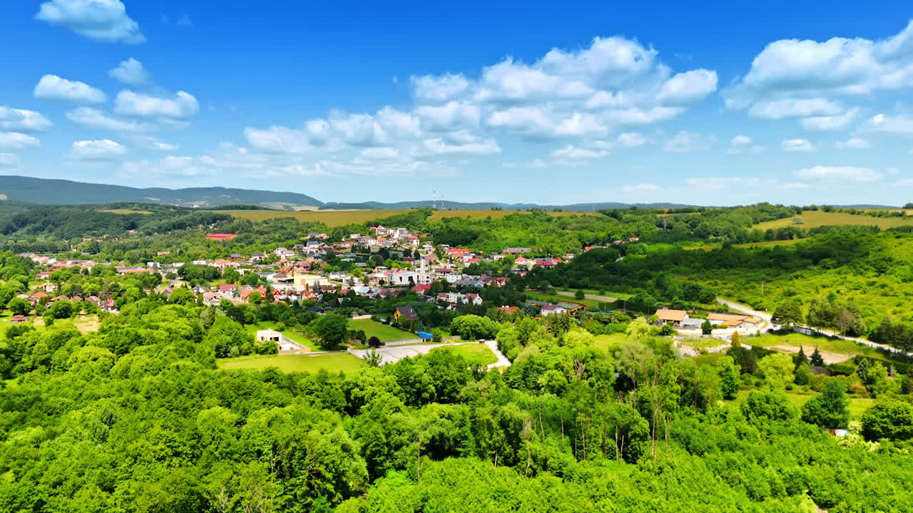 Idyllic scenery of rural area on a beautiful sunny day. Drone footage approaching picturesque village surrounded by lush greenery. Slovakia countryside.