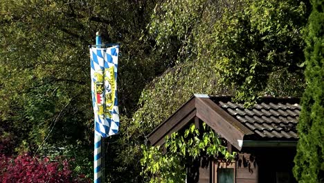 bavarian flag waving in the wind in front of a summerhouse, germany