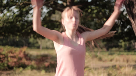 woman doing jumping jacks up close in a park on a sunny day as the sun's rays fall on her face