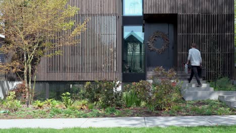 Wide-shot-of-floor-plan-specialist-walking-towards-modern-home-with-a-measuring-equipment