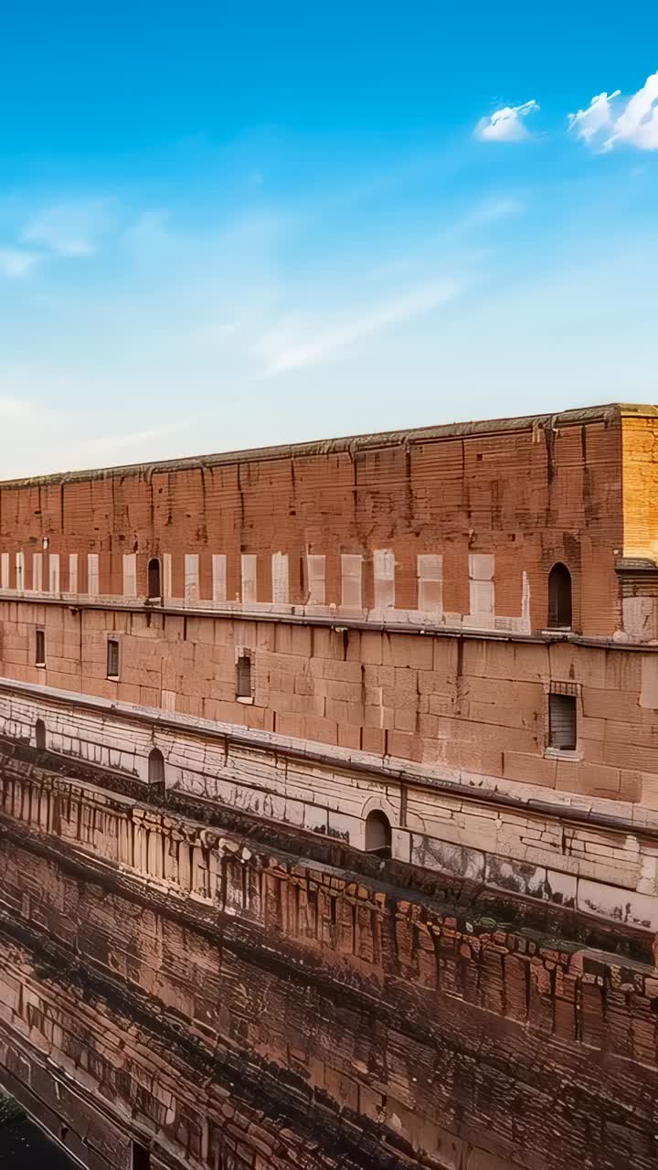 Vertical video: Operator starting panning camera revealing rampart under blue sky, arched openings