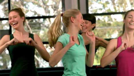 Fit-group-jumping-and-laughing-in-gym