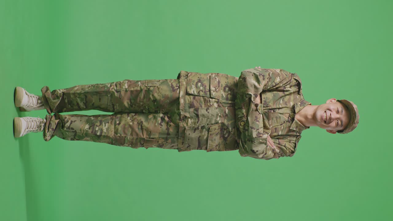 Full Body Of Asian Man Soldier Smiling And Crossing His Arms While Standing In The Green Screen Background Studio