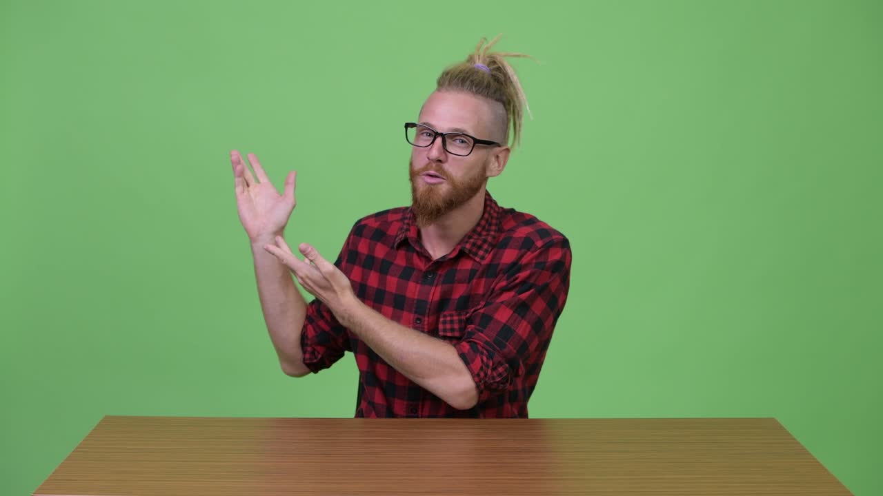 Happy bearded hipster man presenting something against wooden table
