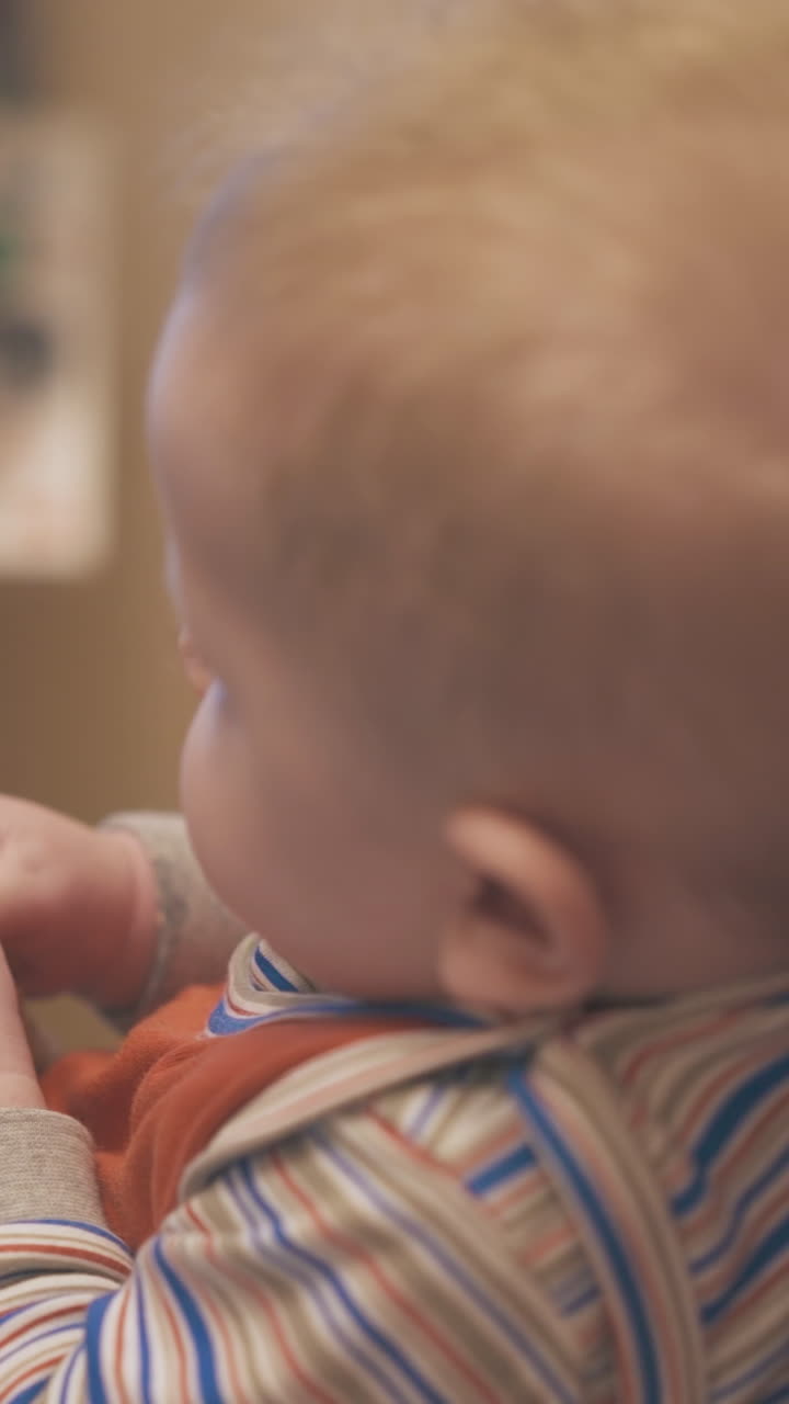 cute funny boy eats tasty boiled corn on cob with mommy watching tv in light room at home extreme close backside view