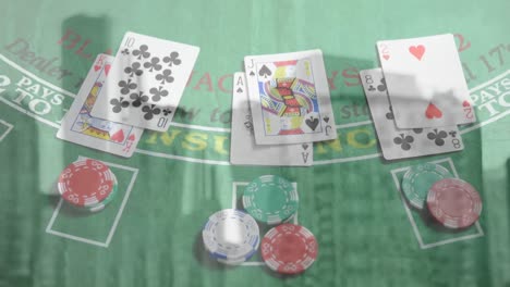 Animation-of-playing-cards-and-chips-on-board-over-cityscape