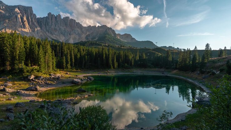 Time Lapse, paesaggio montano mozzafiato nelle Dolomiti italiane, lago alpino, pineta e nuvole sopra le cime
