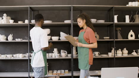joven y mujer haciendo un inventario de cerámica en la tienda de cerámica