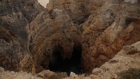 golden sunlight casts a warm glow over rugged limestone cliffs as the sun sets along portugal’s algarve coast
