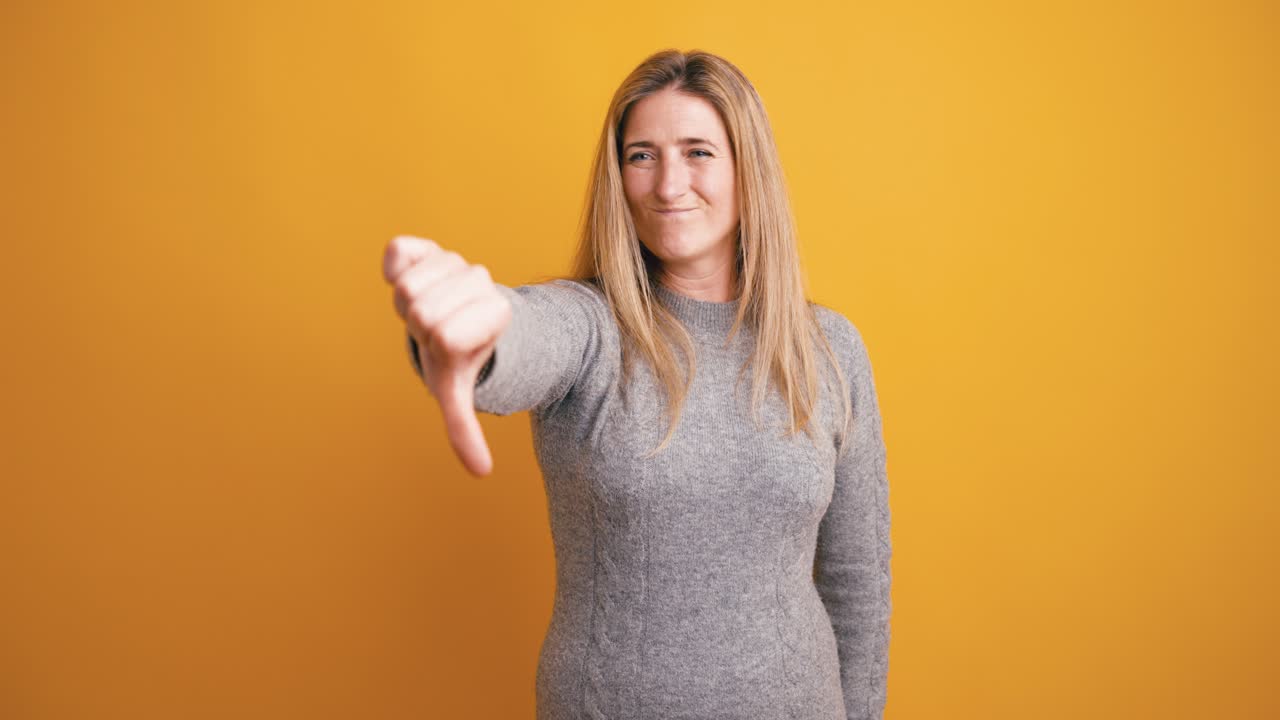 Donna che fa il gesto del pollice verso su sfondo giallo