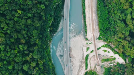 aerial view of a bridge over a river with forest and train tracks