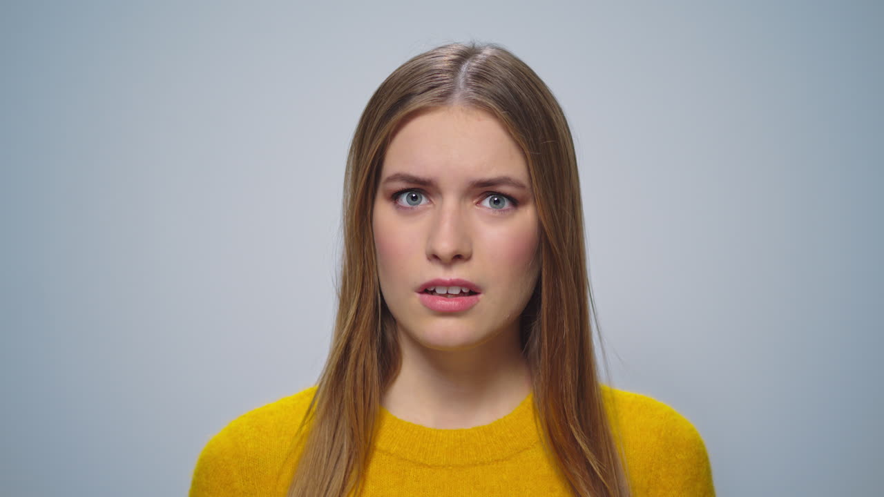 Portrait of displeased woman gesturing on grey background in studio.