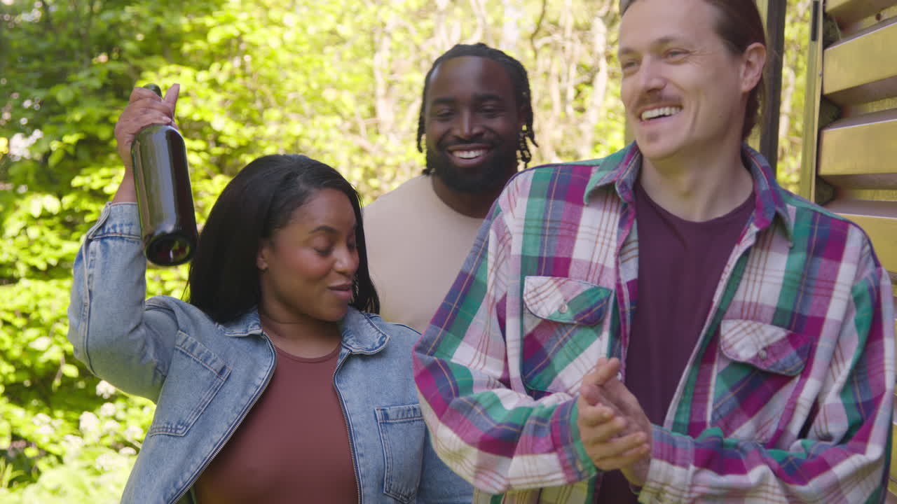 파티 축하 행사를 위해 도착한 와인 병을 들고 있는 다문화 친구 그룹의 야외 촬영