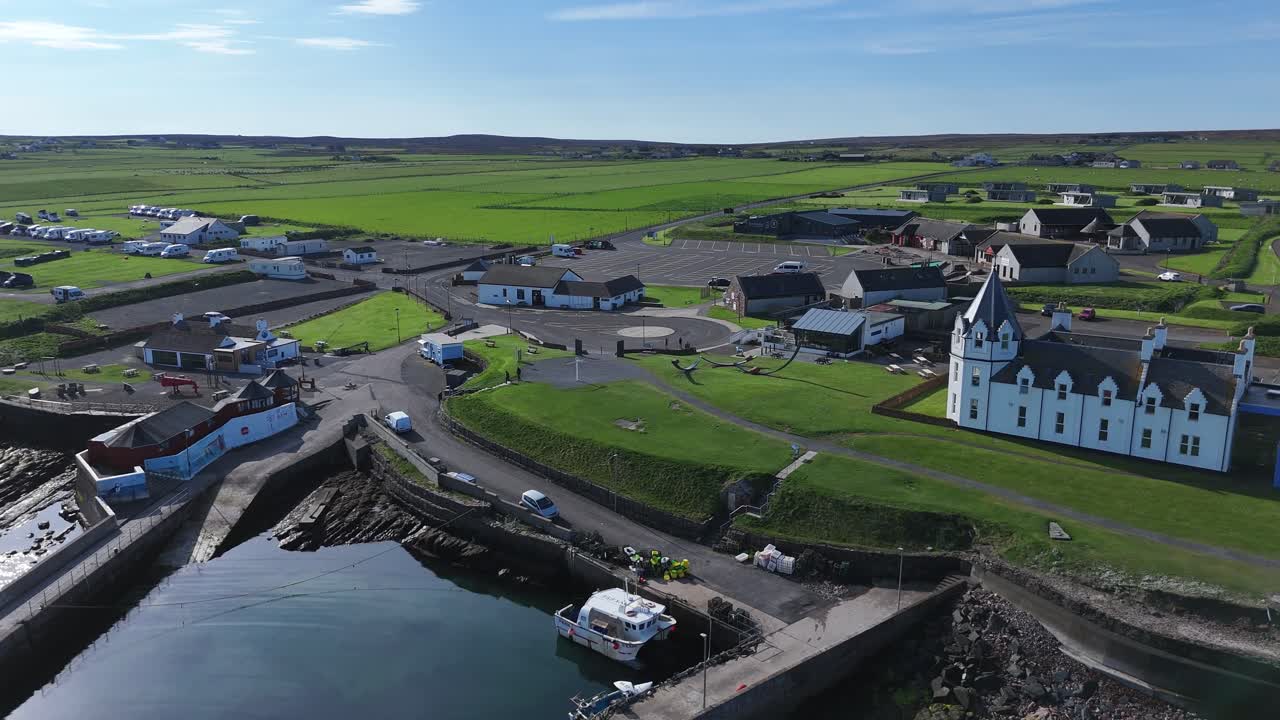 Aerial shot of the John O'Groats Signpost with colourful houses at the harbour