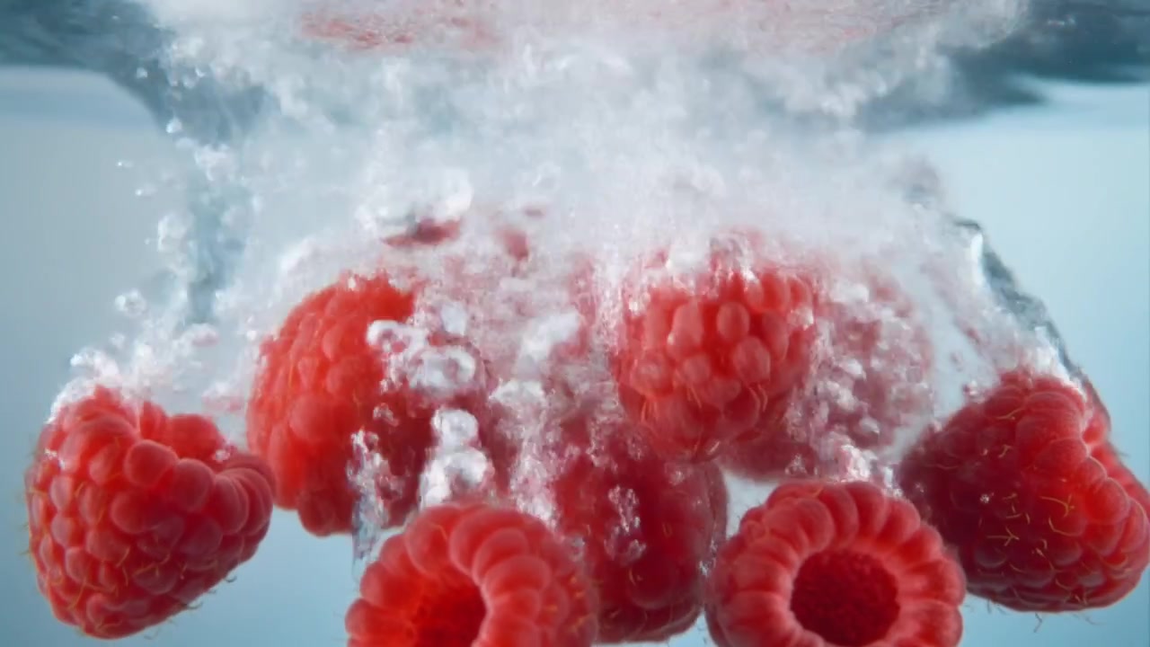 Fresh Raspberries Falling into Clear Water with Bubbles