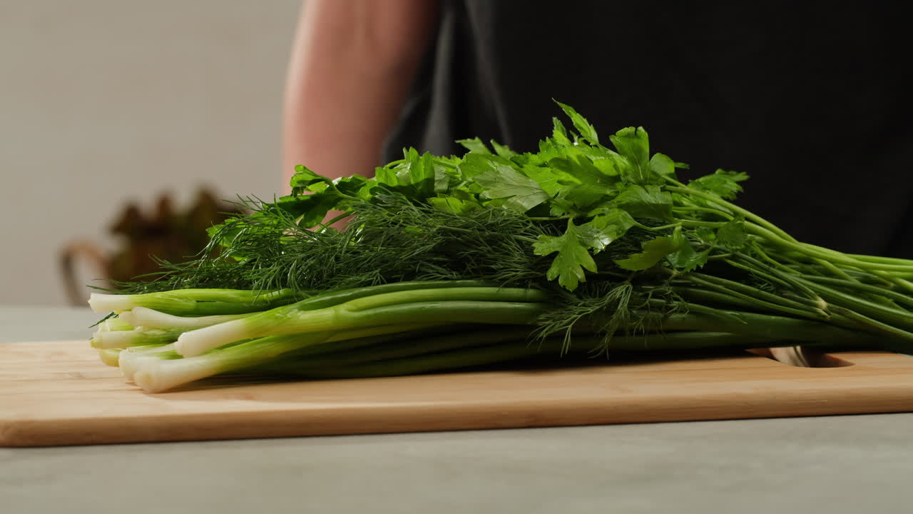 Cutting fresh green onions on a cutting board, close up chef cooking green vegan salad.
