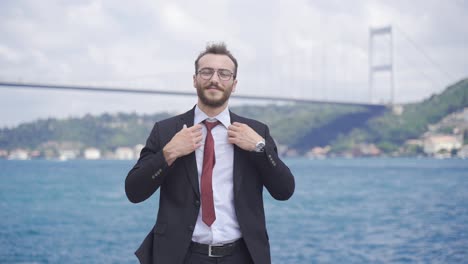 un hombre de negocios arreglando una corbata junto al mar.