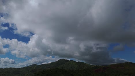Dichte-Wolken-Ziehen-Tagsüber-über-Die-Bewaldeten-Hügel-Und-Bedecken-Den-Blauen-Himmel