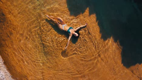 Girl-in-a-natural-rock-pool-next-to-the-sea-in-Kefalonia-Island,-Greece